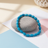 Blue beaded bracelet on a gray stone with a minimal background