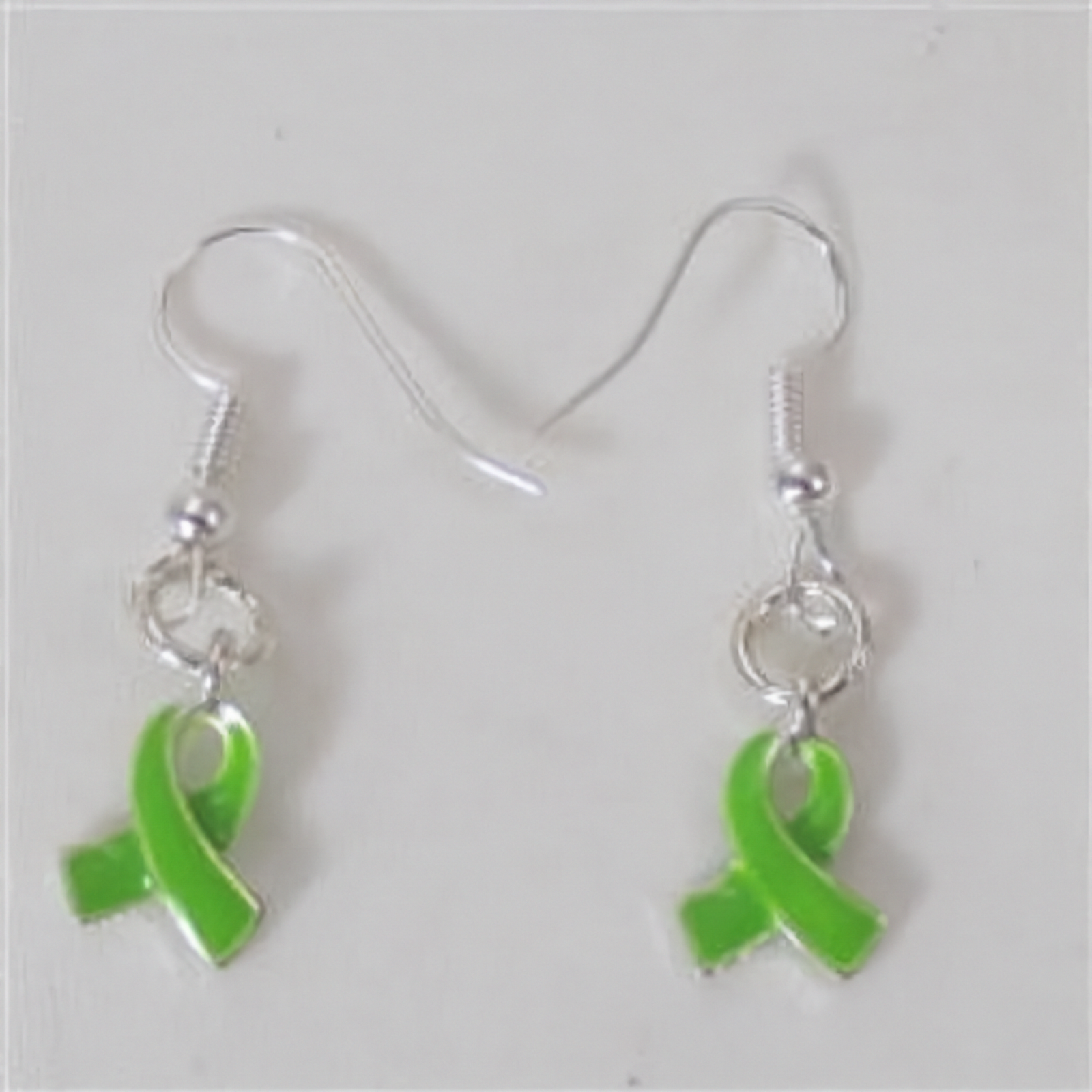 A pair of silver-toned fishhook dangle earrings with bright green awareness ribbon charms, shown on a plain light background.