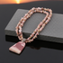 Necklace with pink stone beads and a pendant on a dark surface